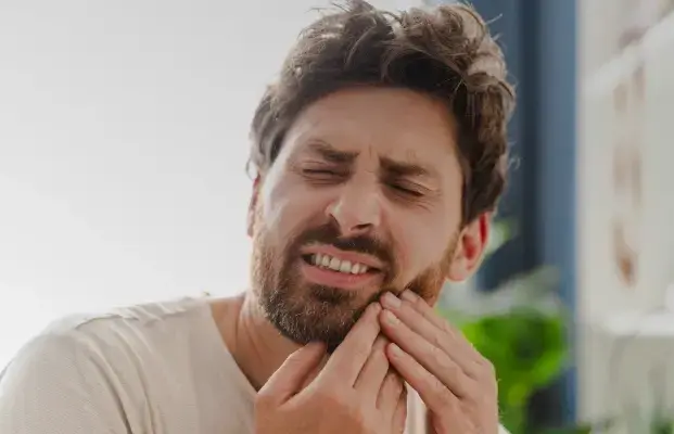 Man holding cheek in pain, experiencing tooth discomfort or dental problems.
